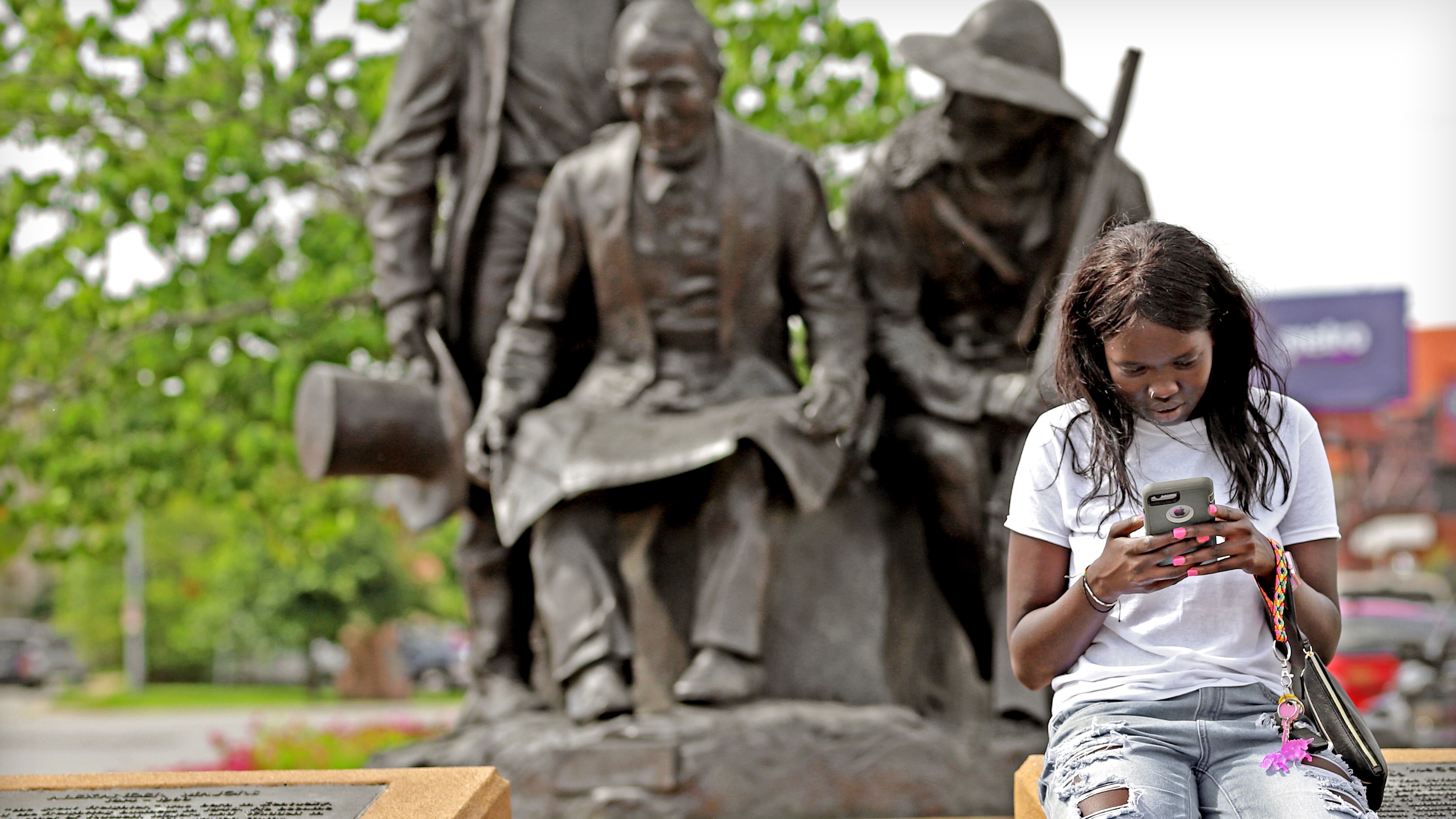 Girl on her phone infront of pioneers statue
